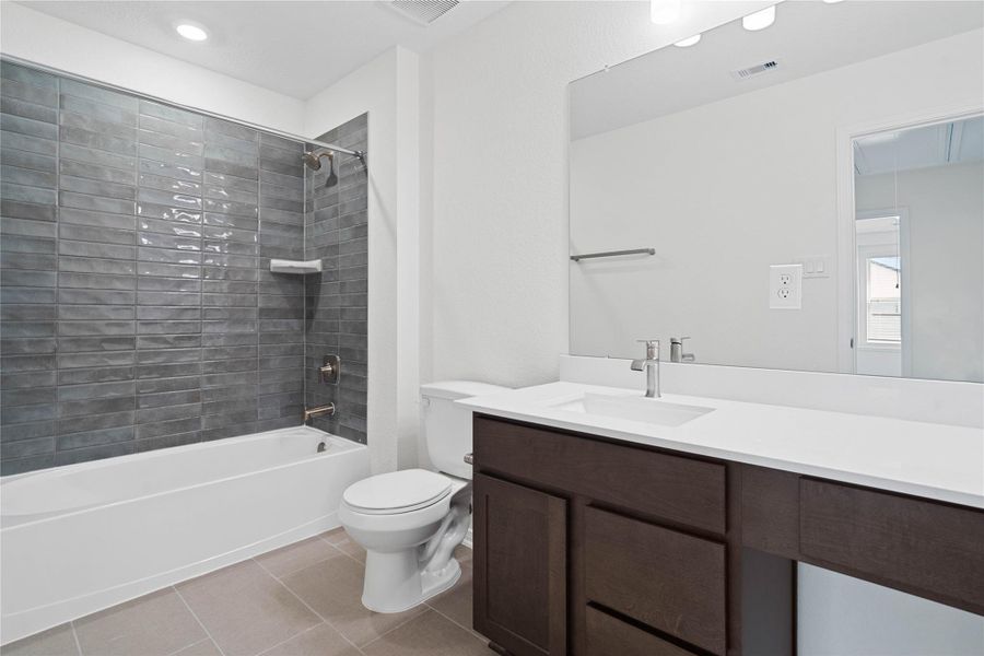 The secondary bathroom showcases tile flooring, a bath/shower combo with a Daltile Mesmerist Charm tile surround, an extended cabinet with knee space and stunning light countertop, a stylish mirror, sleek fixtures, and contemporary finishes throughout. The secondary bathroom showcases tile flooring, a bath/shower combo with a Daltile Mesmerist Charm tile surround, an extended cabinet with knee space and stunning light countertop, a stylish mirror, sleek fixtures, and contemporary finishes throughout.