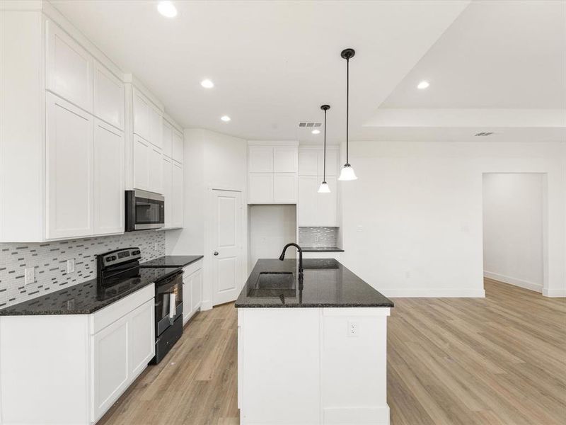 Kitchen featuring backsplash, black range with electric cooktop, recessed lighting, white cabinetry, and dark stone counters