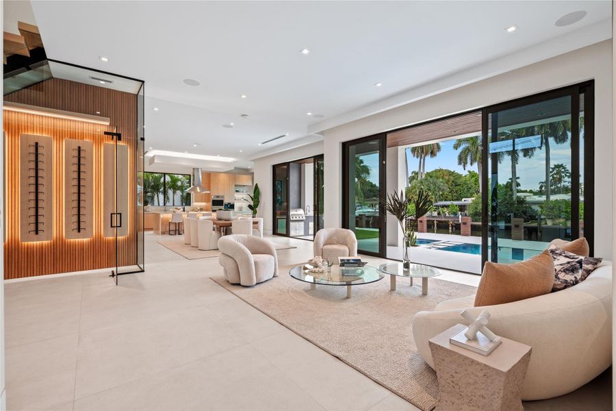 Open-concept great room with floor-to-ceiling glass doors, custom wine display, designer finishes, and seamless indoor-outdoor flow to the waterfront pool and entertaining areas. Open-concept great room with floor-to-ceiling glass doors, custom wine display, designer finishes, and seamless indoor-outdoor flow to the waterfront pool and entertaining areas.