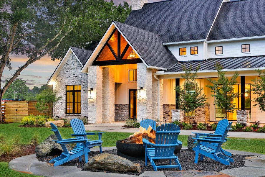 Elegantly-styled home with a stone and brick exterior and a large welcoming front porch. The landscaped yard includes a cozy outdoor seating area to entertain around a custom fire pit. Set against a backdrop of mature trees and surrounded by nature, it is the perfect setting for relaxed entertainment. Elegantly-styled home with a stone and brick exterior and a large welcoming front porch. The landscaped yard includes a cozy outdoor seating area to entertain around a custom fire pit. Set against a backdrop of mature trees and surrounded by nature, it is the perfect setting for relaxed entertainment.