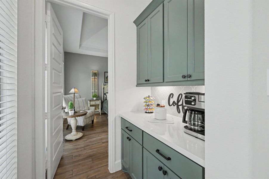 Around the corner from the kitchen is this custom coffee bar. This was added during construction and is tucked away for easy access to a cup of coffee first thing in the morning. Coffee not your thing, it can serve as a Butler's Pantry or bar. The cabinets were painted the same color as the island and the quartz counter top and backsplash match the kitchen. Around the corner from the kitchen is this custom coffee bar. This was added during construction and is tucked away for easy access to a cup of coffee first thing in the morning. Coffee not your thing, it can serve as a Butler's Pantry or bar. The cabinets were painted the same color as the island and the quartz counter top and backsplash match the kitchen.