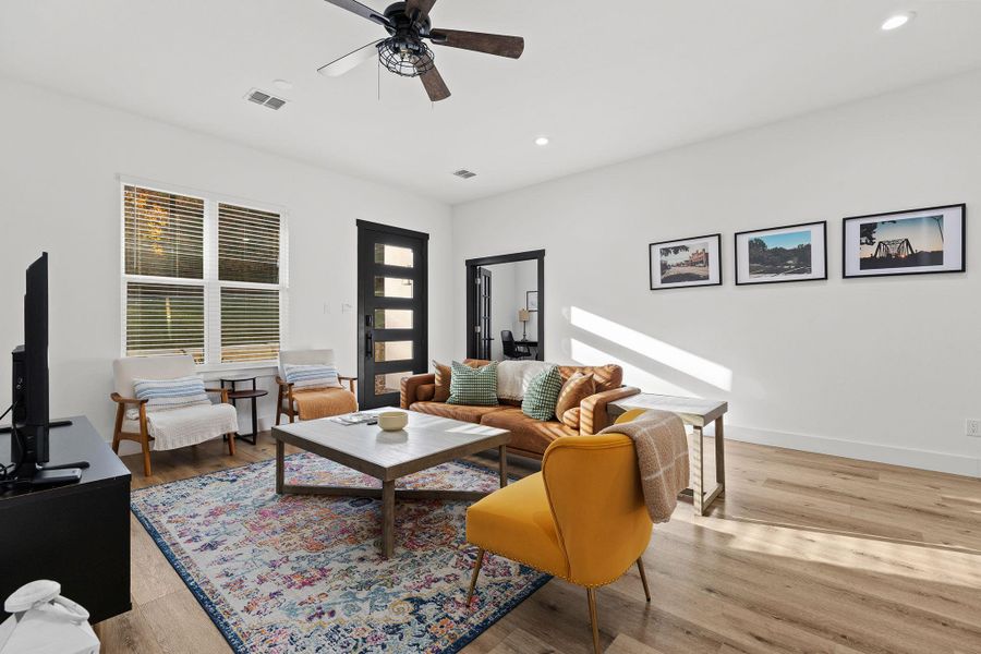 Living room with light wood-style floors, ceiling fan, and recessed lighting