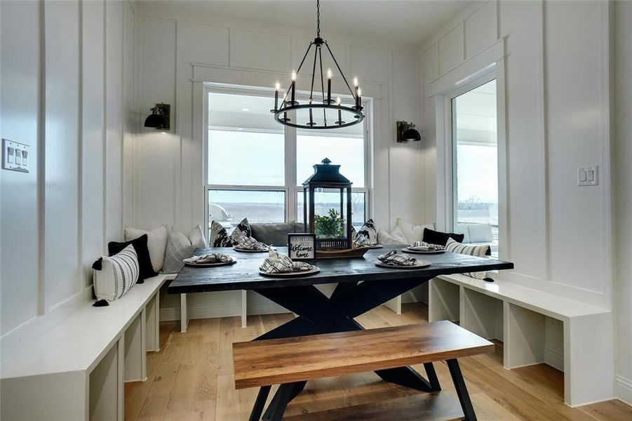 Dining space with a decorative wall, light wood-style floors, and a chandelier