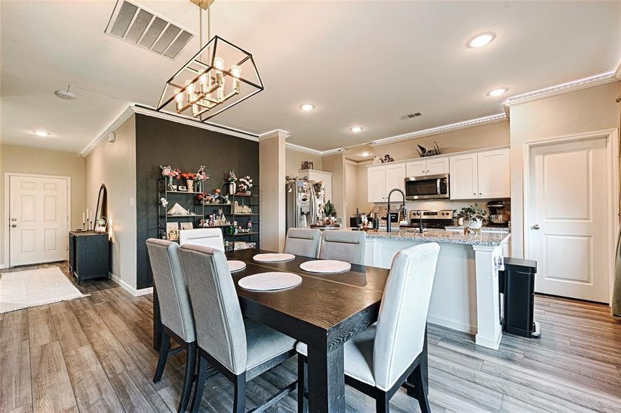 Dining area featuring recessed lighting, light wood-style floors, crown molding, and a chandelier Dining area featuring recessed lighting, light wood-style floors, crown molding, and a chandelier