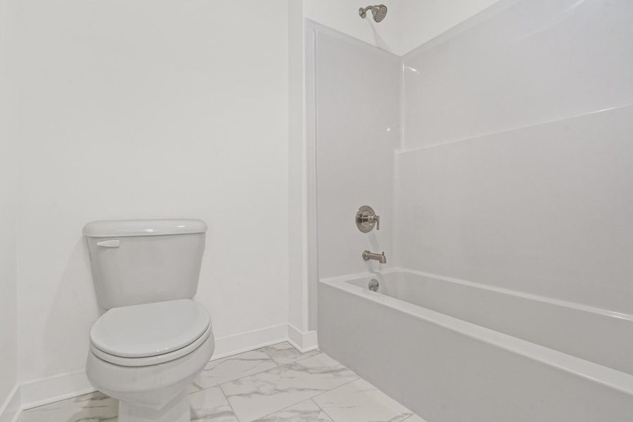 Bathroom featuring light marble finish floors and bathing tub / shower combination