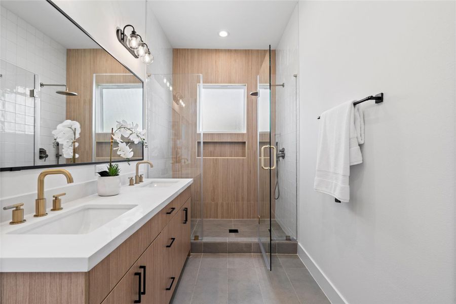 Champagne bronze Delta shower fixtures add a touch of sophisticated warmth and timeless elegance to the ensuite, perfectly complementing the timeless design