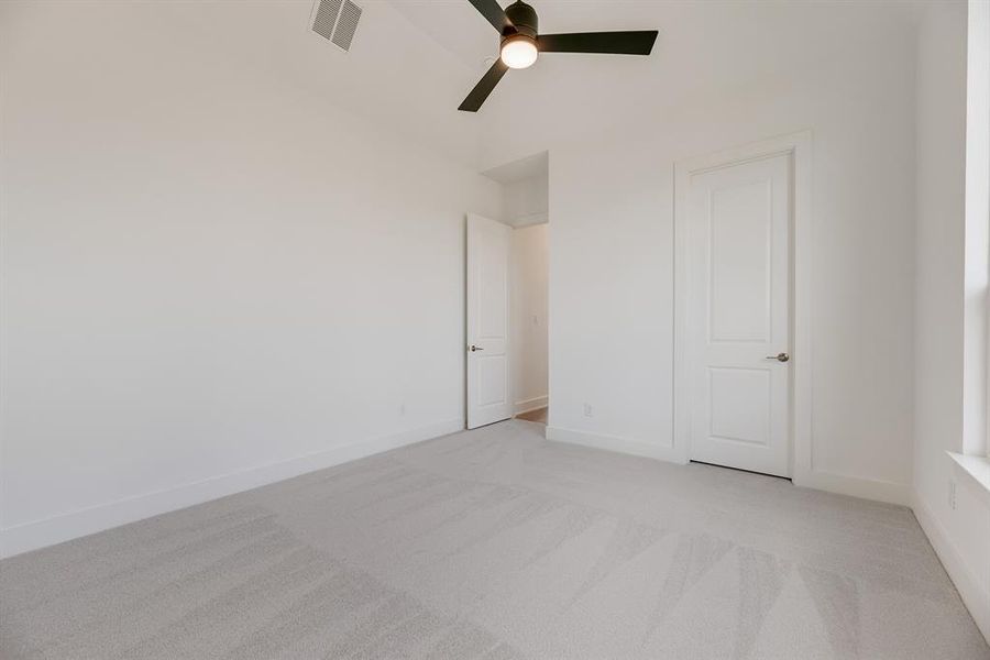 Unfurnished bedroom with light colored carpet and a ceiling fan