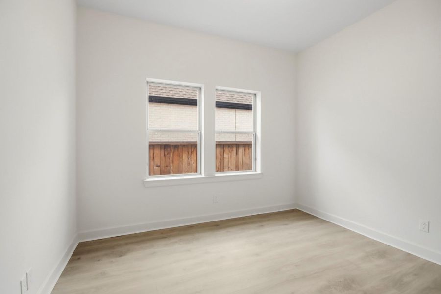 Bright and inviting bedroom with large windows, neutral walls, and elegant wood flooring, perfect for a cozy bedroom or a home office.