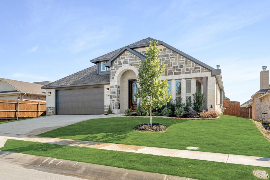 Single-story home with stone and brick exterior, arched entry, two-car garage, and landscaped front yard Single-story home with stone and brick exterior, arched entry, two-car garage, and landscaped front yard