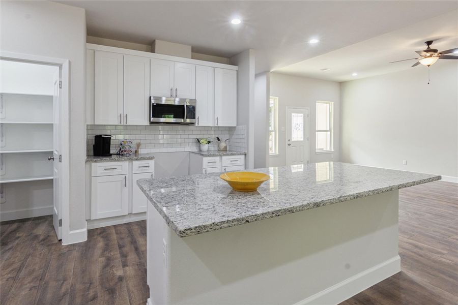 This kitchen boasts a stunning granite island, perfect for gatherings, with a convenient walk-in pantry just to the left.