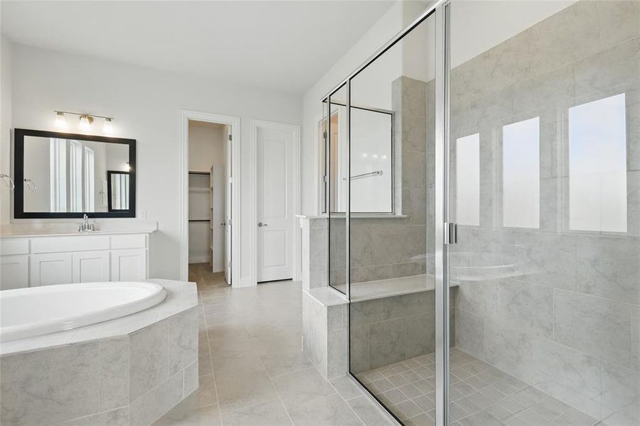 Full bath with a walk in closet, tile patterned flooring, vanity, a bath, and a stall shower Full bath with a walk in closet, tile patterned flooring, vanity, a bath, and a stall shower