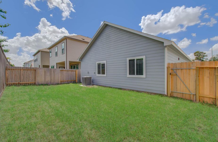 Charming backyard with lush green lawn, ideal for outdoor activities and relaxation, enclosed by a wooden fence for privacy.