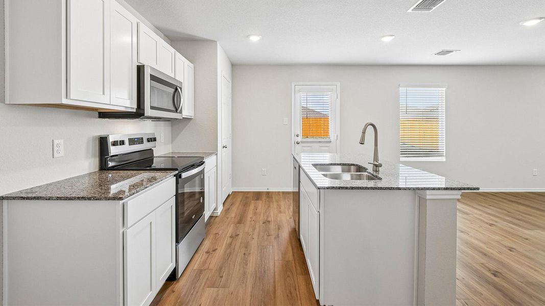 A well-lit kitchen boasts granite countertops and stainless steel appliances, creating a highly functional culinary space.