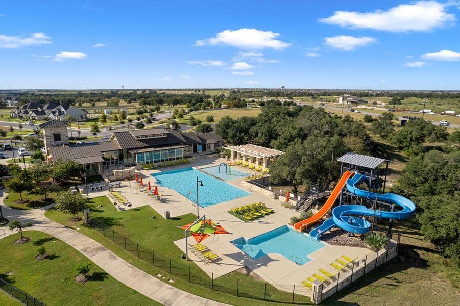An aerial perspective reveals a vibrant community pool with slides, recreational facilities, and inviting green spaces. An aerial perspective reveals a vibrant community pool with slides, recreational facilities, and inviting green spaces.