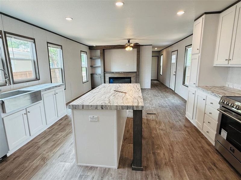 Kitchen featuring wood finished floors, electric range, light countertops, a sink, and a ceiling fan