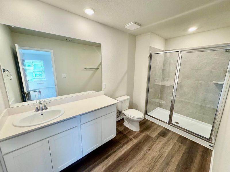 Full bathroom with wood finished floors, vanity, a stall shower, and recessed lighting