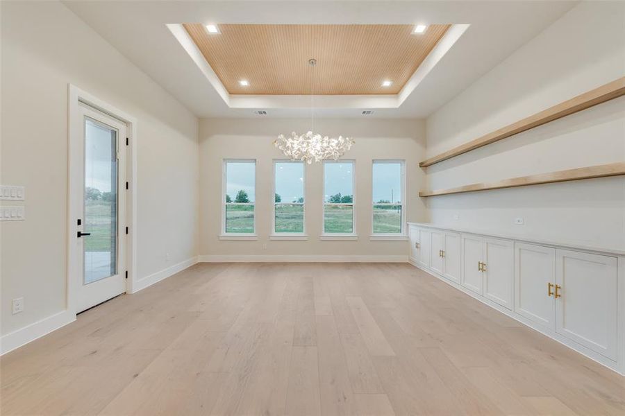 Unfurnished dining area with a tray ceiling, a chandelier, wooden ceiling, healthy amount of natural light, and light wood finished floors Unfurnished dining area with a tray ceiling, a chandelier, wooden ceiling, healthy amount of natural light, and light wood finished floors