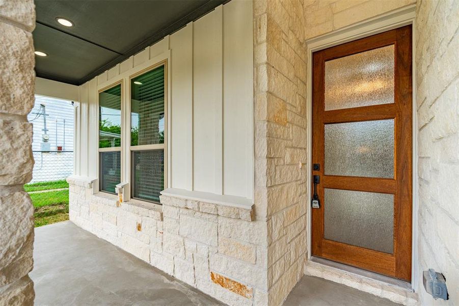 View of exterior entry with a porch and stone siding