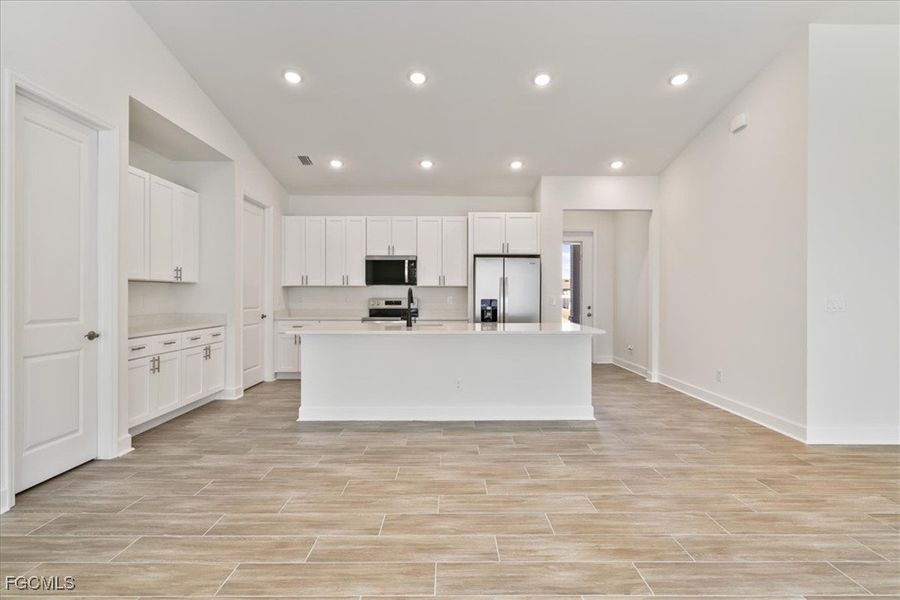 Kitchen featuring white cabinetry, appliances with stainless steel finishes, a kitchen island with sink, recessed lighting, and wood finish floors