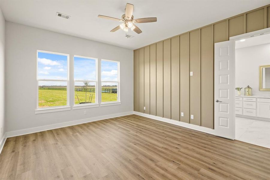 Tranquility awaits in this spacious and stylish Primary Retreat. The space boasts LVP flooring, an accent wall, 5-blade ceiling fan, and a trio of windows with a serene country view. The double doors ahead lead to the spa-like Primary Bath.