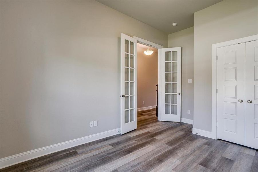 Unfurnished bedroom featuring french doors, a closet, and hardwood / wood-style floors