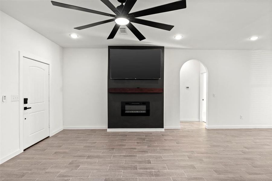 Unfurnished living room with recessed lighting, arched walkways, light wood-style flooring, and ceiling fan