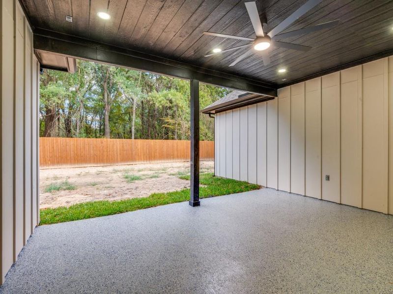 Fenced backyard with cover patio area and a ceiling fan.