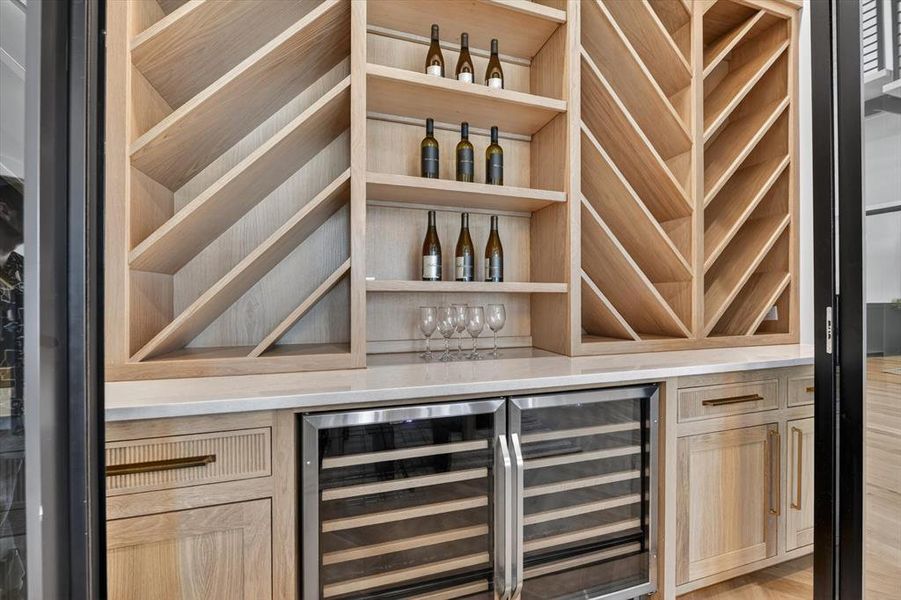 Built-in light wood cabinetry featuring open shelving and specialized bottle storage Built-in light wood cabinetry featuring open shelving and specialized bottle storage