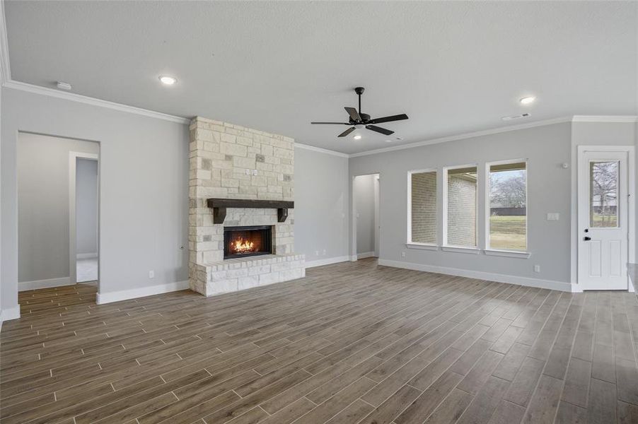 Unfurnished living room with wood finish floors, crown molding, a fireplace, ceiling fan, and recessed lighting