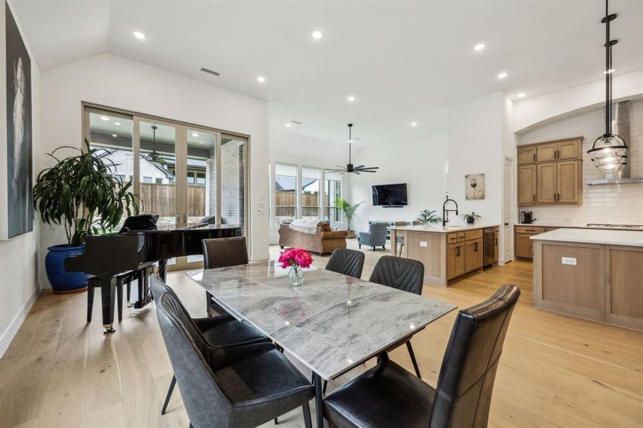 Dining room with lofted ceiling, ceiling fan, light wood-style floors, and recessed lighting