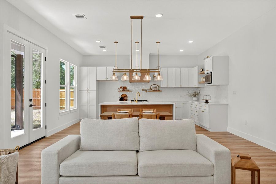 Living room with light wood-style floors, recessed lighting, and french doors