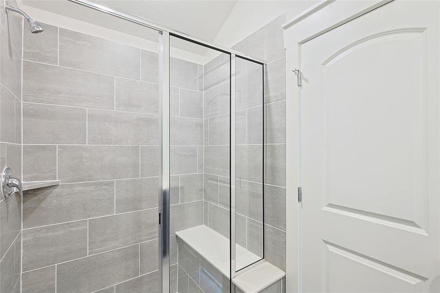 Bathroom featuring walk in shower and vaulted ceiling