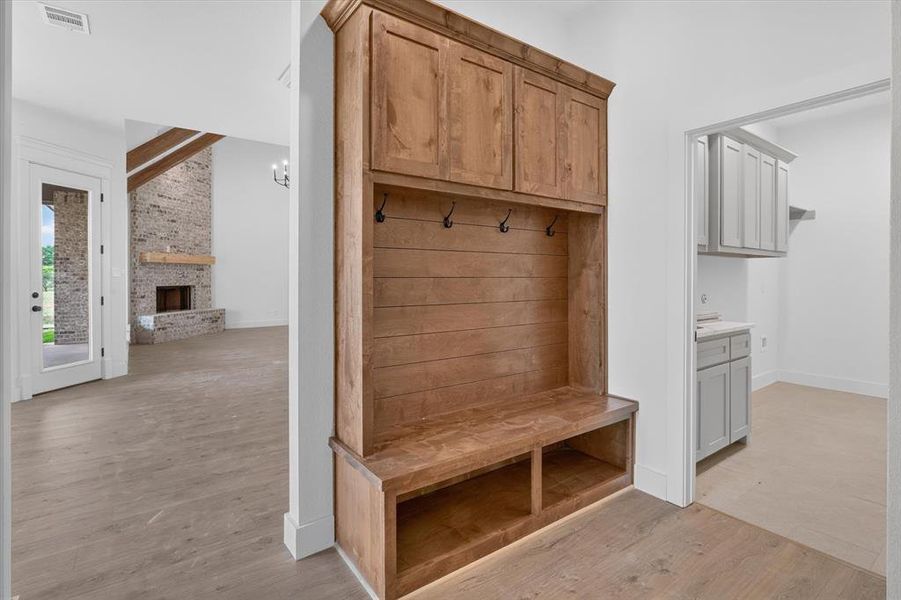 Built-in wood-finish hall tree with upper cabinetry, storage bench, and coat hooks Built-in wood-finish hall tree with upper cabinetry, storage bench, and coat hooks