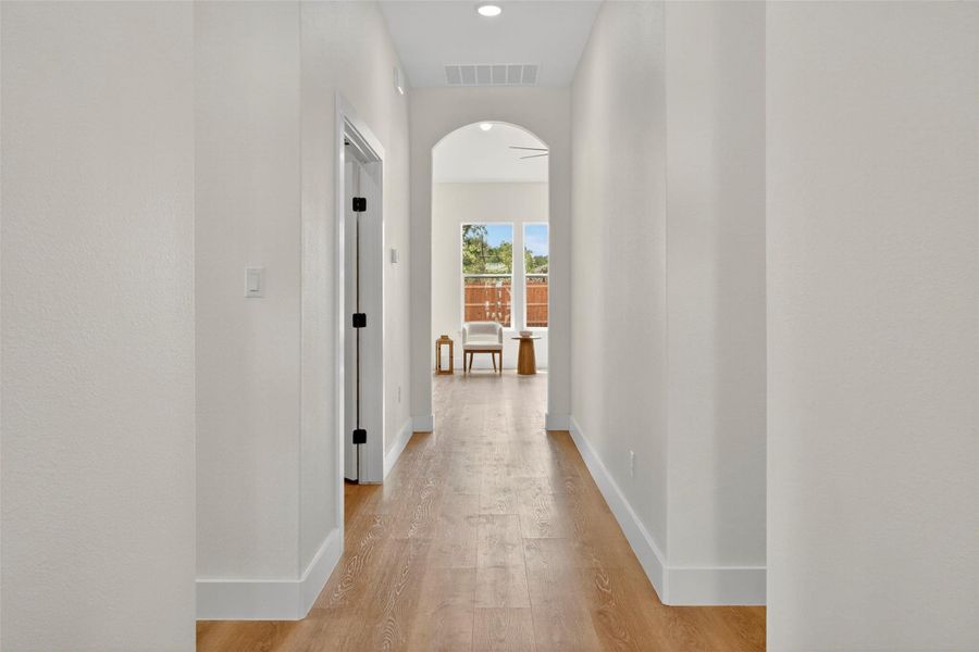 Hall featuring arched walkways, light wood finished floors, and recessed lighting