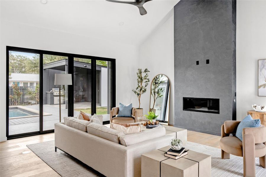 Living room featuring light wood-style flooring, a fireplace, a ceiling fan, high vaulted ceiling, and recessed lighting