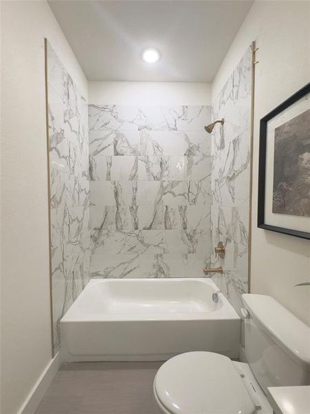 Bathroom with toilet and tiled shower / bath combo