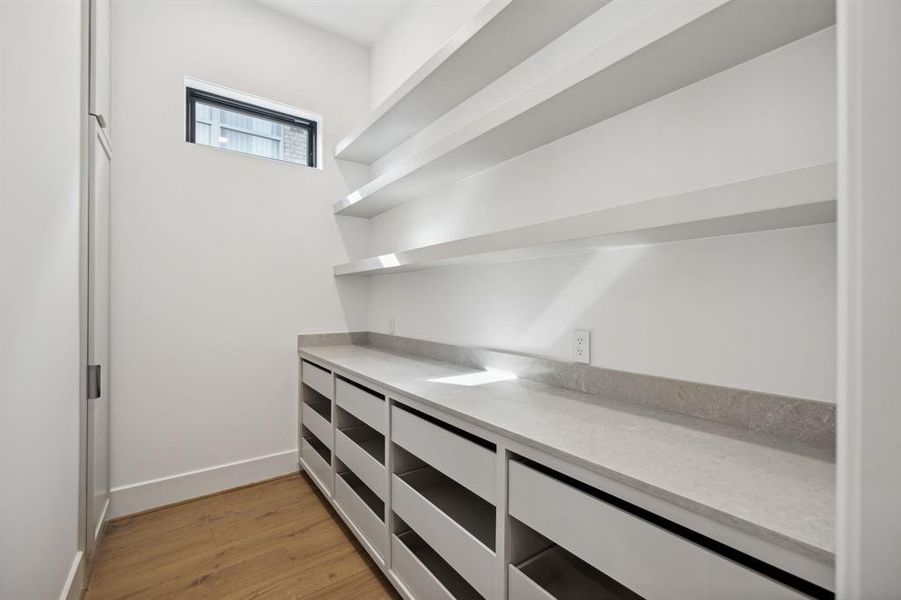 The spacious pantry features ample storage space with open shelves lining the top half of the walls and a series of drawers along the bottom.You also have plenty of countertop space for prepping.