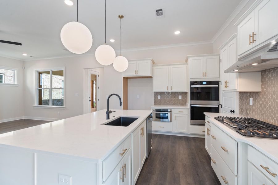 Kitchen featuring crown molding, dark wood-type flooring, white cabinets, backsplash, and recessed lighting Kitchen featuring crown molding, dark wood-type flooring, white cabinets, backsplash, and recessed lighting