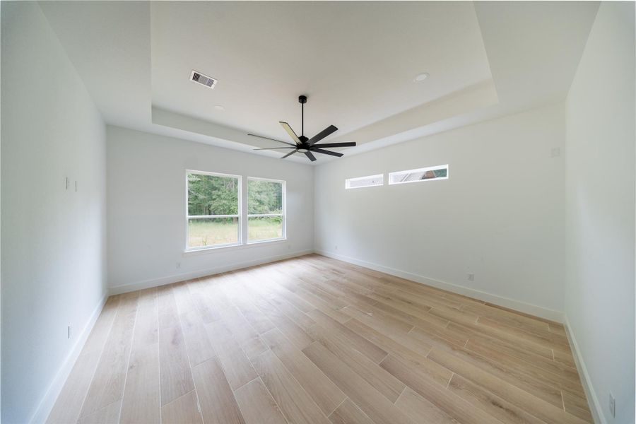 Primary bedroom offers high tray ceilings with upgraded tile flooring