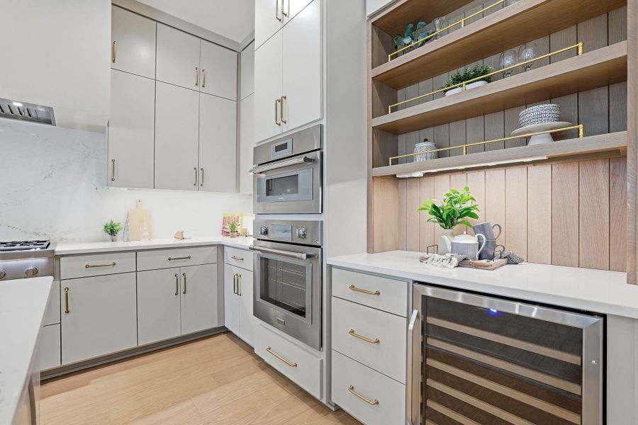 Kitchen featuring wine cooler, open shelves, light wood-style floors, stainless steel appliances, and light stone counters