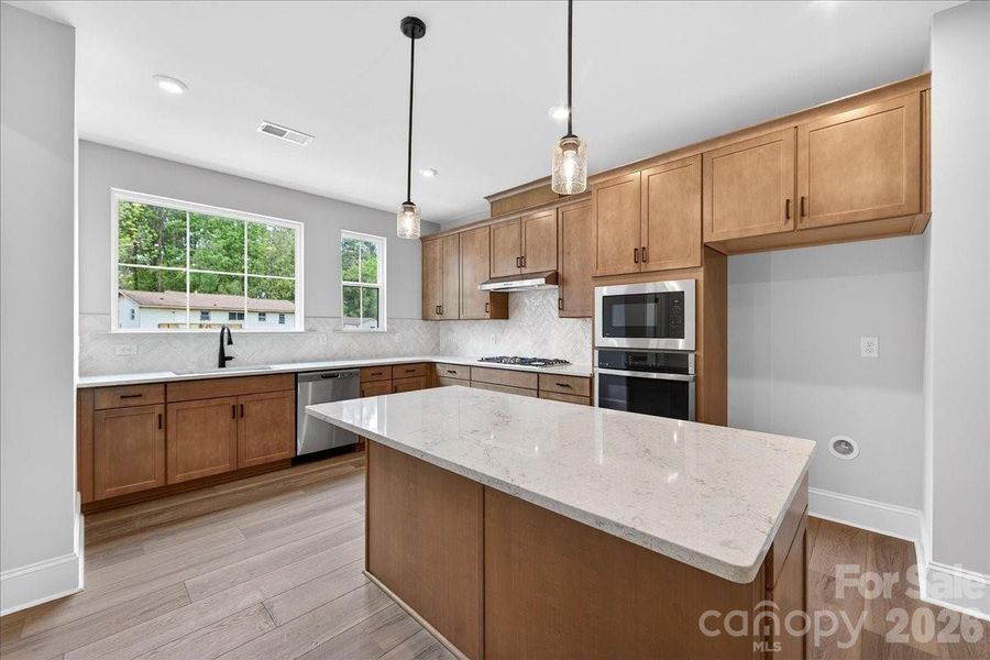 Gourmet kitchen with warm brown cabinets and white quartz countertops