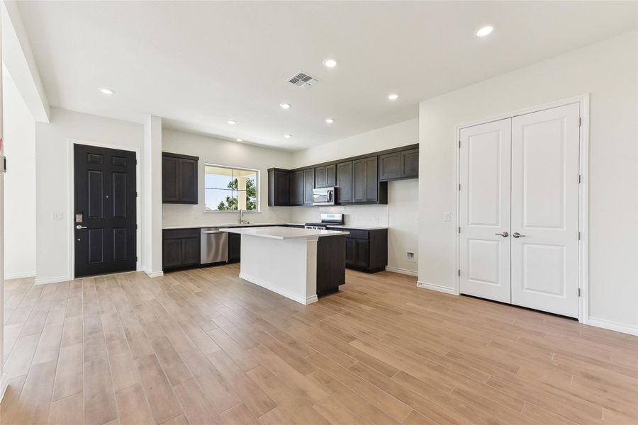 Kitchen with light countertops, a center island, light wood-style floors, and stainless steel appliances Kitchen with light countertops, a center island, light wood-style floors, and stainless steel appliances