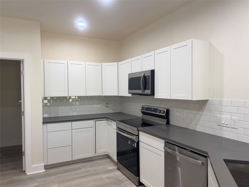 A well-appointed kitchen showcasing contemporary white cabinetry and sleek stainless steel appliances.