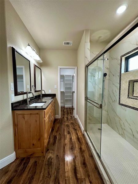 Bathroom featuring vanity, wood-type flooring, and a shower with door