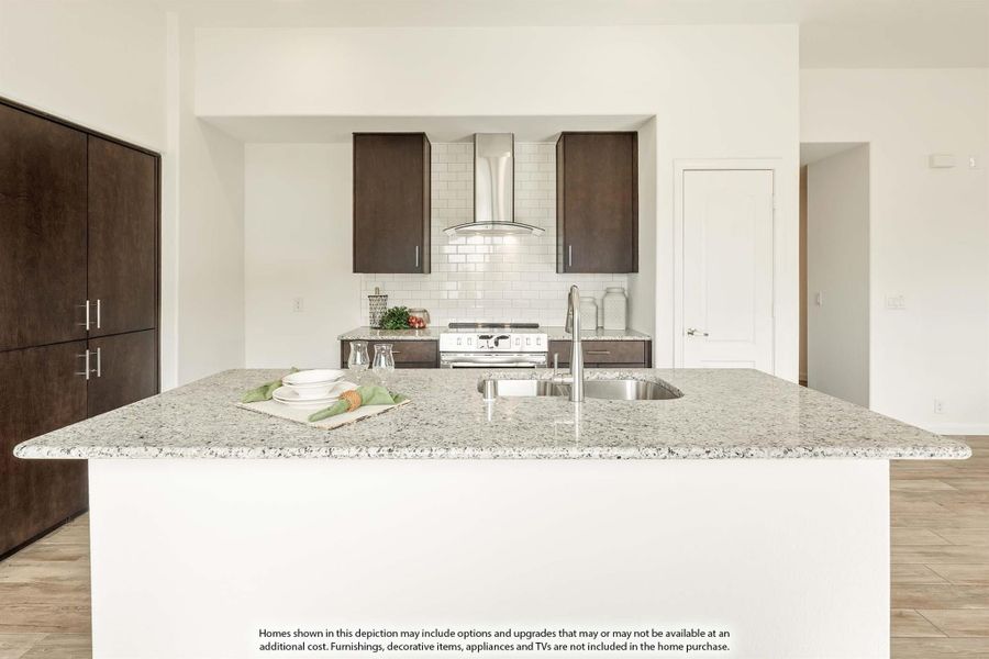 Kitchen with large granite island, dark wood cabinets, white subway tile backsplash, and stainless steel range hood