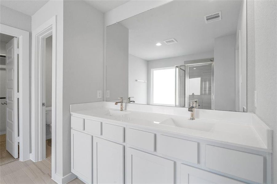 This large primary bath is spacious enough to share! With separate vanities, large closet space, plentiful cabinet and counter space, you are sure to have private area while sharing this bathroom!