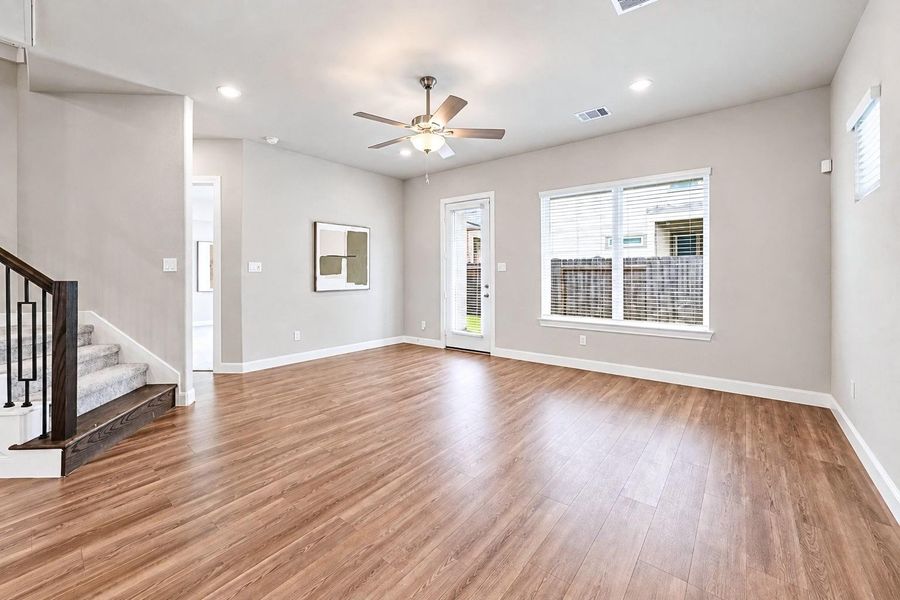 Living Room is filled with natural light from large windows and connects seamlessly to the dining area and kitchen.