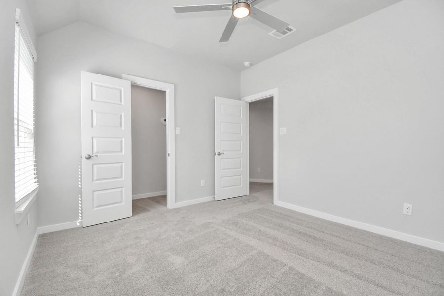 Secondary bedroom features plush carpeting, large windows that let in plenty of natural light, bright paint, and spacious closets. Sample photo of completed home with similar floor plan. Actual colors and selections may vary.