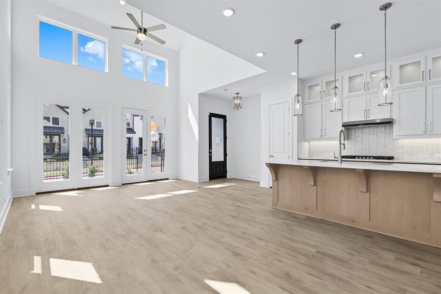 Kitchen featuring glass insert cabinets, a kitchen breakfast bar, light wood-style flooring, backsplash, and white cabinets Kitchen featuring glass insert cabinets, a kitchen breakfast bar, light wood-style flooring, backsplash, and white cabinets