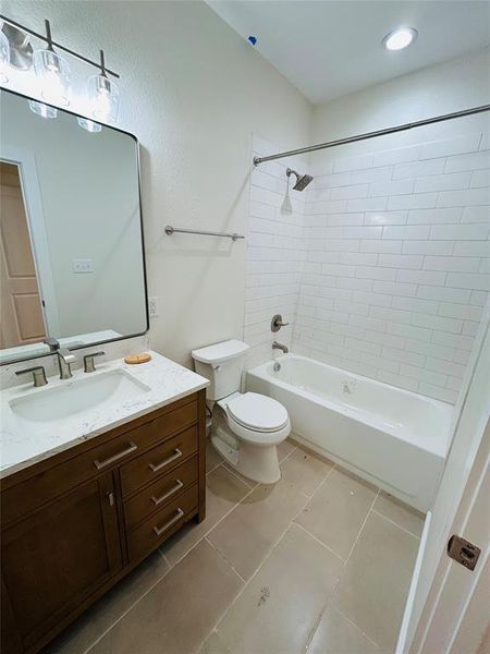 Full bathroom with tile patterned floors, vanity, toilet, and tiled shower / bath